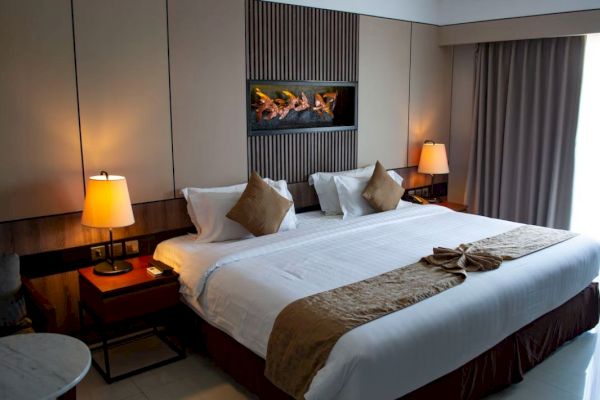 A neatly arranged hotel room with a king-sized bed, decorative pillows, lamps, and a modern wall design and curtains.