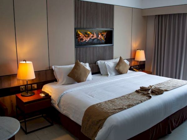 A neatly arranged hotel room with a king-sized bed, decorative pillows, lamps, and a modern wall design and curtains.
