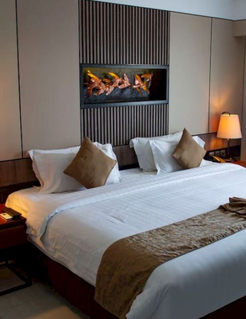 A cozy hotel room with a large bed, two bedside tables with lamps, and a decorative piece above the bed.