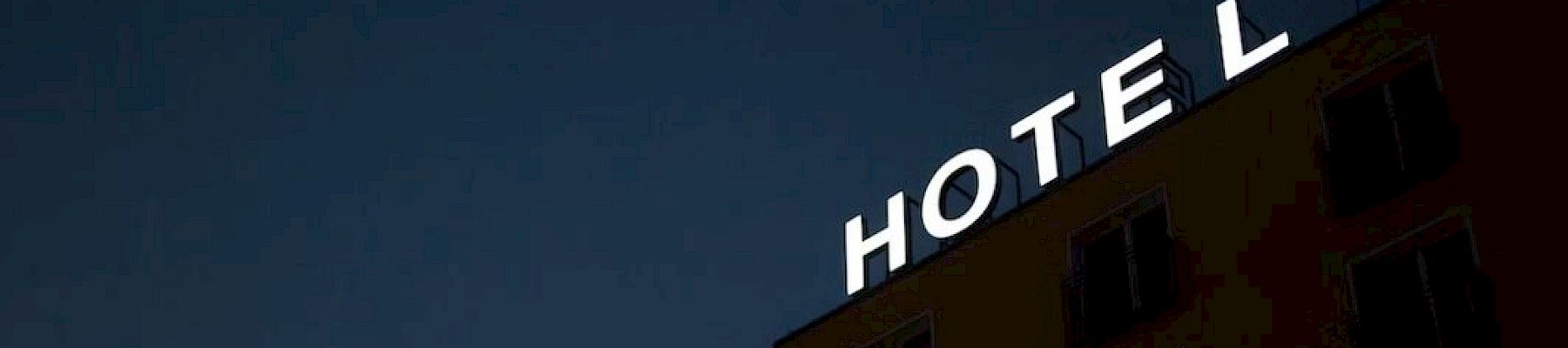 A building with a sign reading "HOTEL," missing the letter "L," against a dark sky.