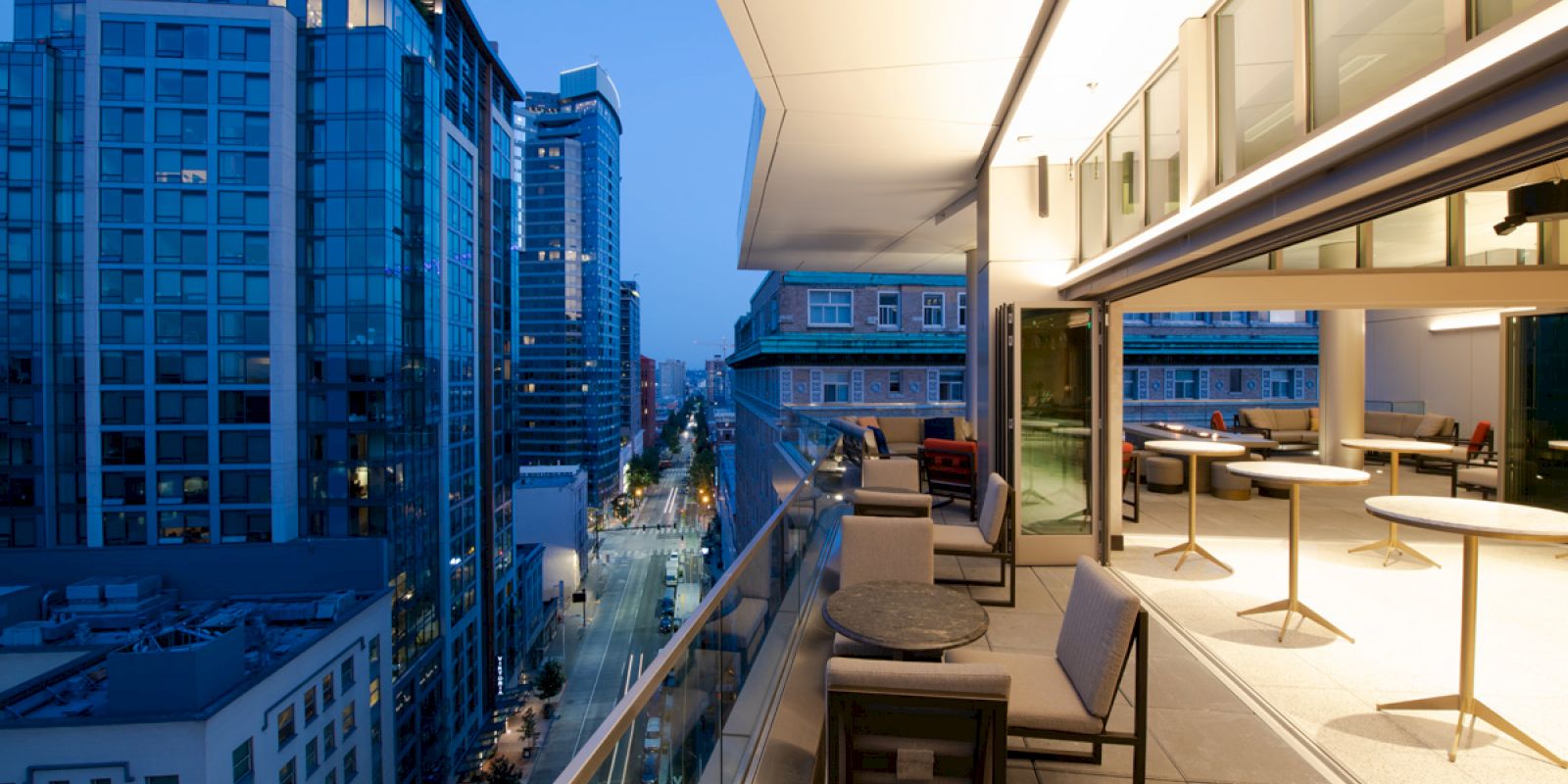 A modern balcony overlooking a cityscape at dusk, with stylish seating and soft lighting creating a cozy atmosphere.