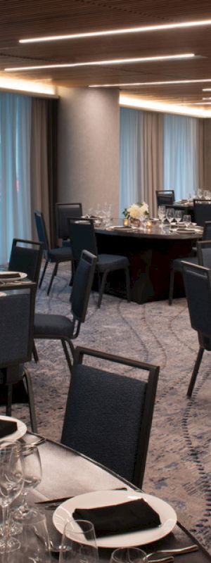 A dining room set up for an event with round tables, elegant place settings, and dim lighting, creating a formal atmosphere.